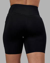 Woman wearing Elite Run High-Rise 7" Short Pockets - Black | Model:Charlize | Size:S