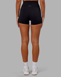 Woman wearing Elixir Ultra High-Rise 4" Short Pockets - Black | Model:Kirstyn | Size:S