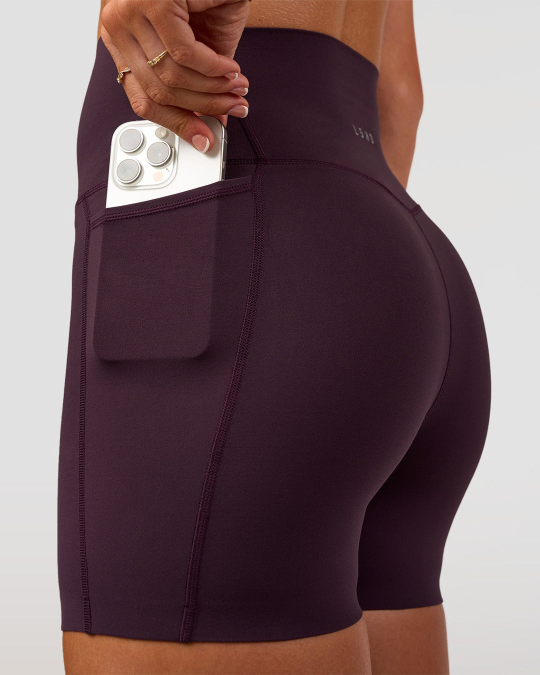 Woman wearing Elixir Ultra High-Rise 4" Short Pockets - Midnight Plum | Model:Emelia | Size:S