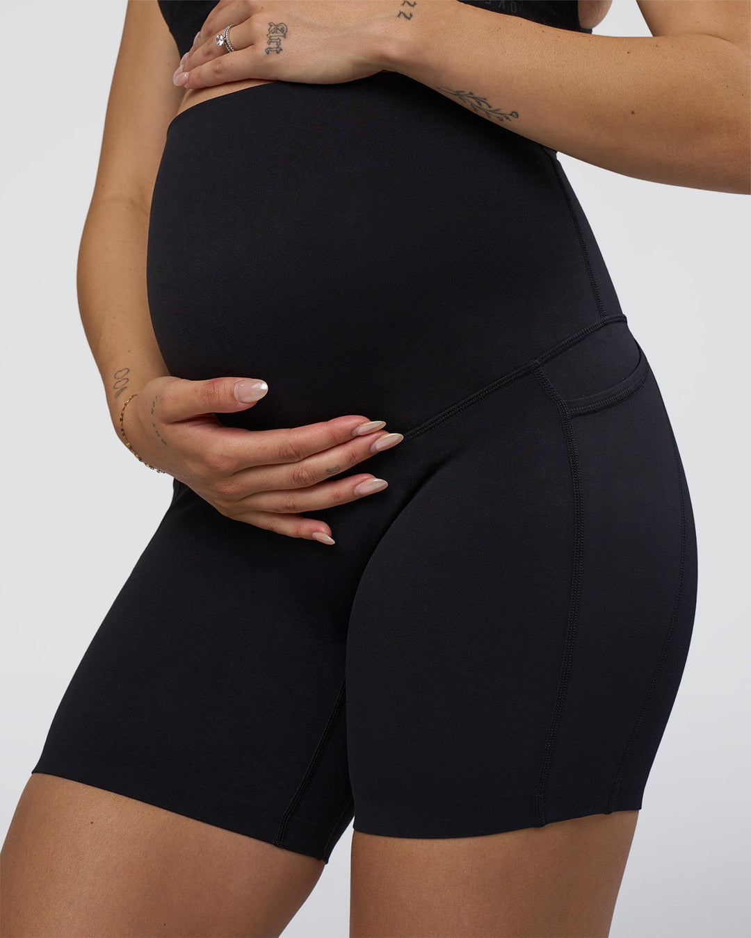 Woman wearing Elixir Ultra High-Rise Maternity 6&quot; Short Pockets - Black | Model:Kitahna | Size:S
