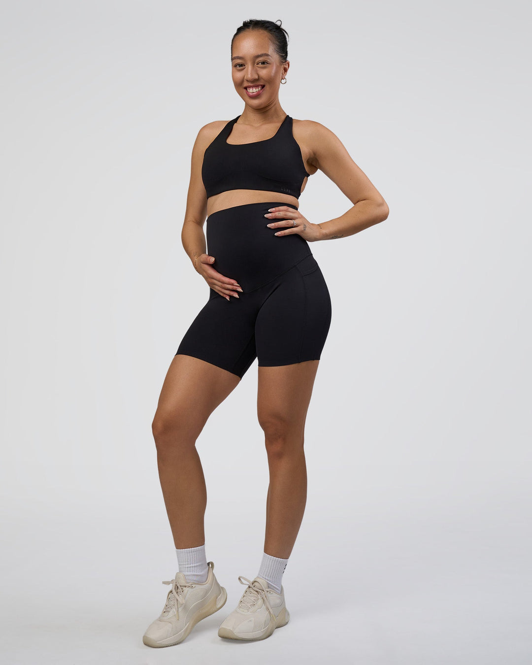 Woman wearing Elixir Ultra High-Rise Maternity 6&quot; Short Pockets - Black | Model:Kitahna | Size:S