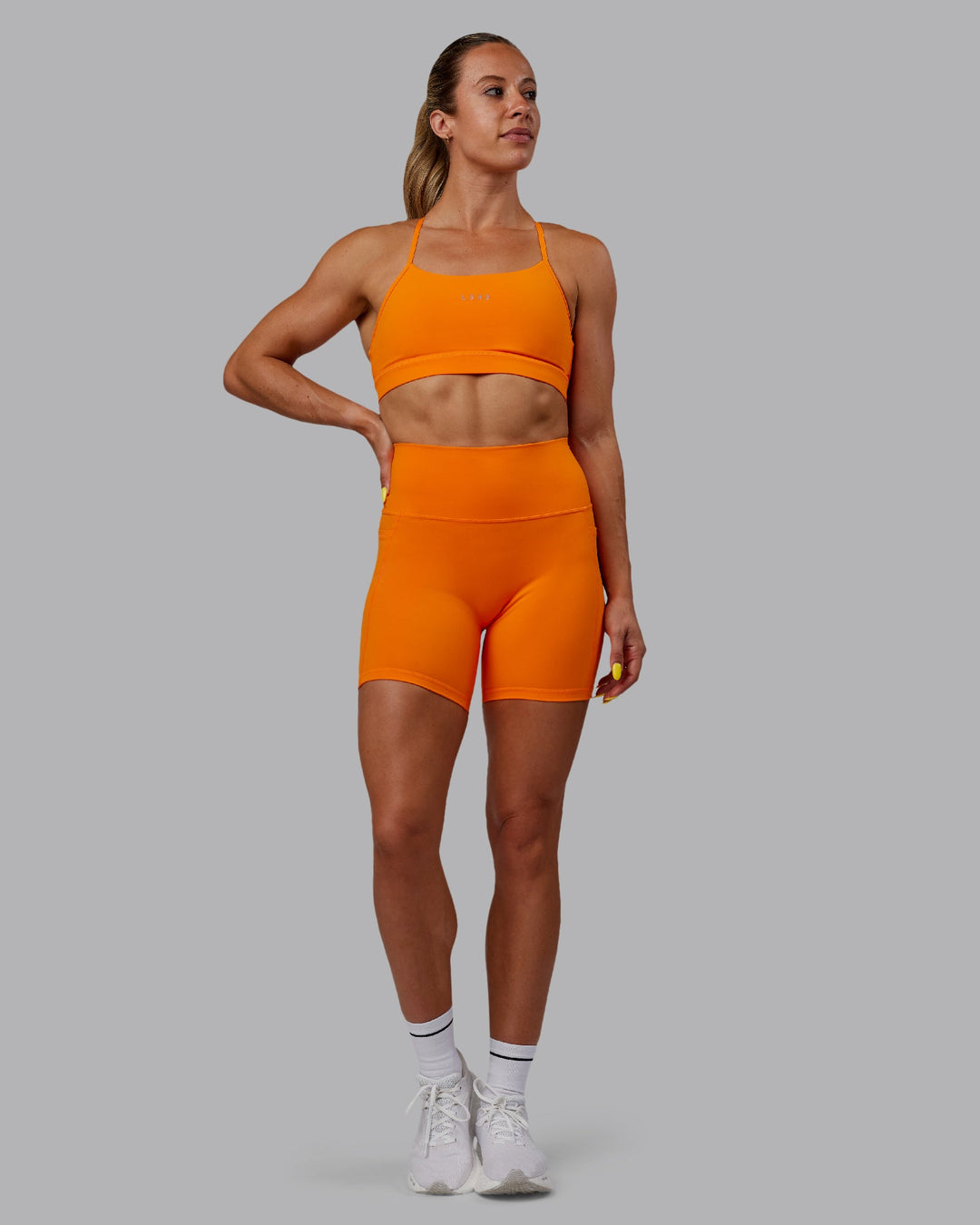 Woman wearing Fusion Ultra High-Rise 6&quot; Short Pockets - Vibrant Orange | Model:Bree | Size:S