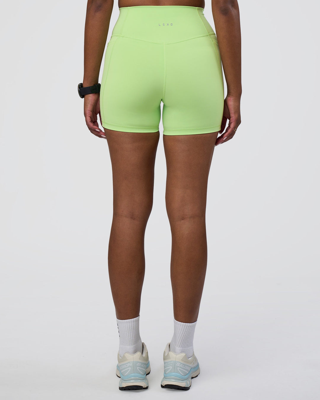Woman wearing Fusion Ultra High-Rise 4&quot; Short Pockets - Solar Lime | Model:Rica | Size:S