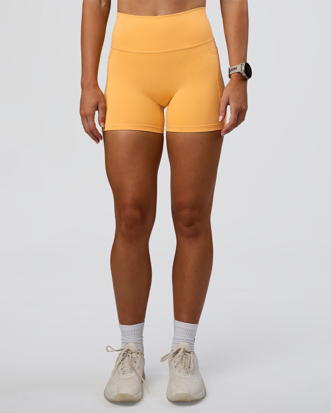 Woman wearing Fusion Ultra High-Rise 4&quot; Short Pockets - Warm Apricot | Model:Emelia | Size:S