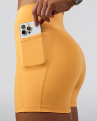 Woman wearing Fusion Ultra High-Rise 4" Short Pockets - Warm Apricot | Model:Emelia | Size:S