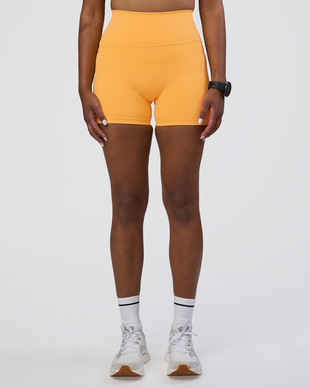 Woman wearing Fusion Ultra High-Rise 4&quot; Short Pockets - Warm Apricot | Model:Rica | Size:S