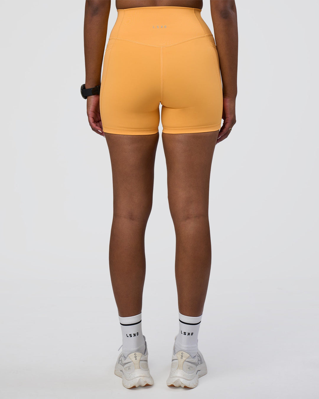 Woman wearing Fusion Ultra High-Rise 4&quot; Short Pockets - Warm Apricot | Model:Rica | Size:S