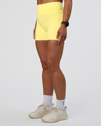 Woman wearing Fusion Ultra High-Rise 4" Short Pockets - Yellow Fizz | Set:true | Angle:side | Model:Sav | Size:S