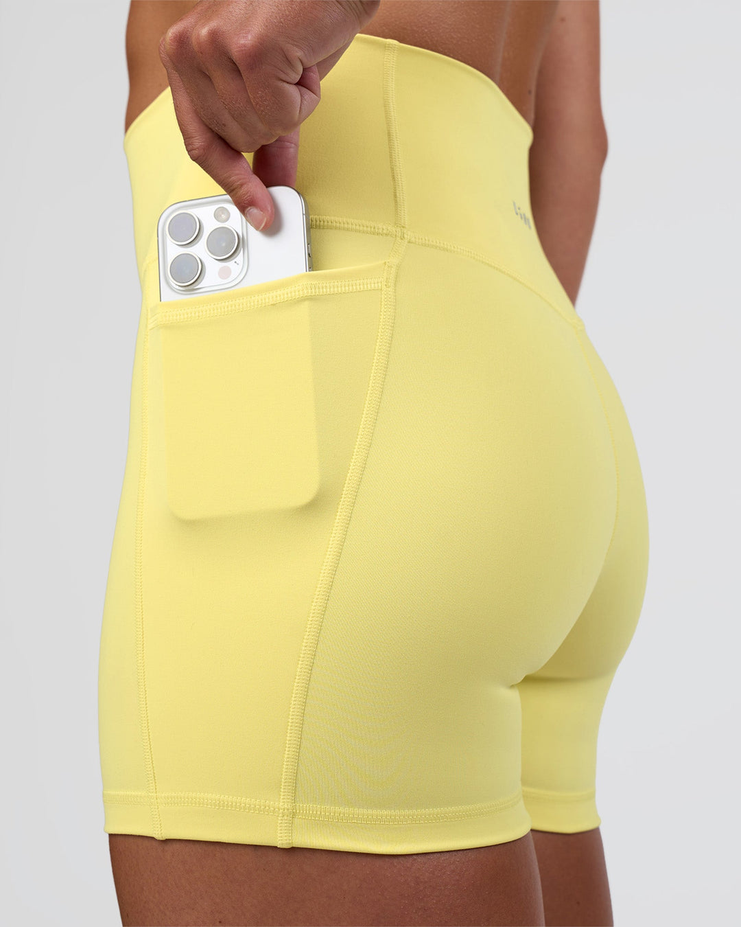 Woman wearing Fusion Ultra High-Rise 4&quot; Short Pockets - Yellow Fizz | Model:Sav | Size:S