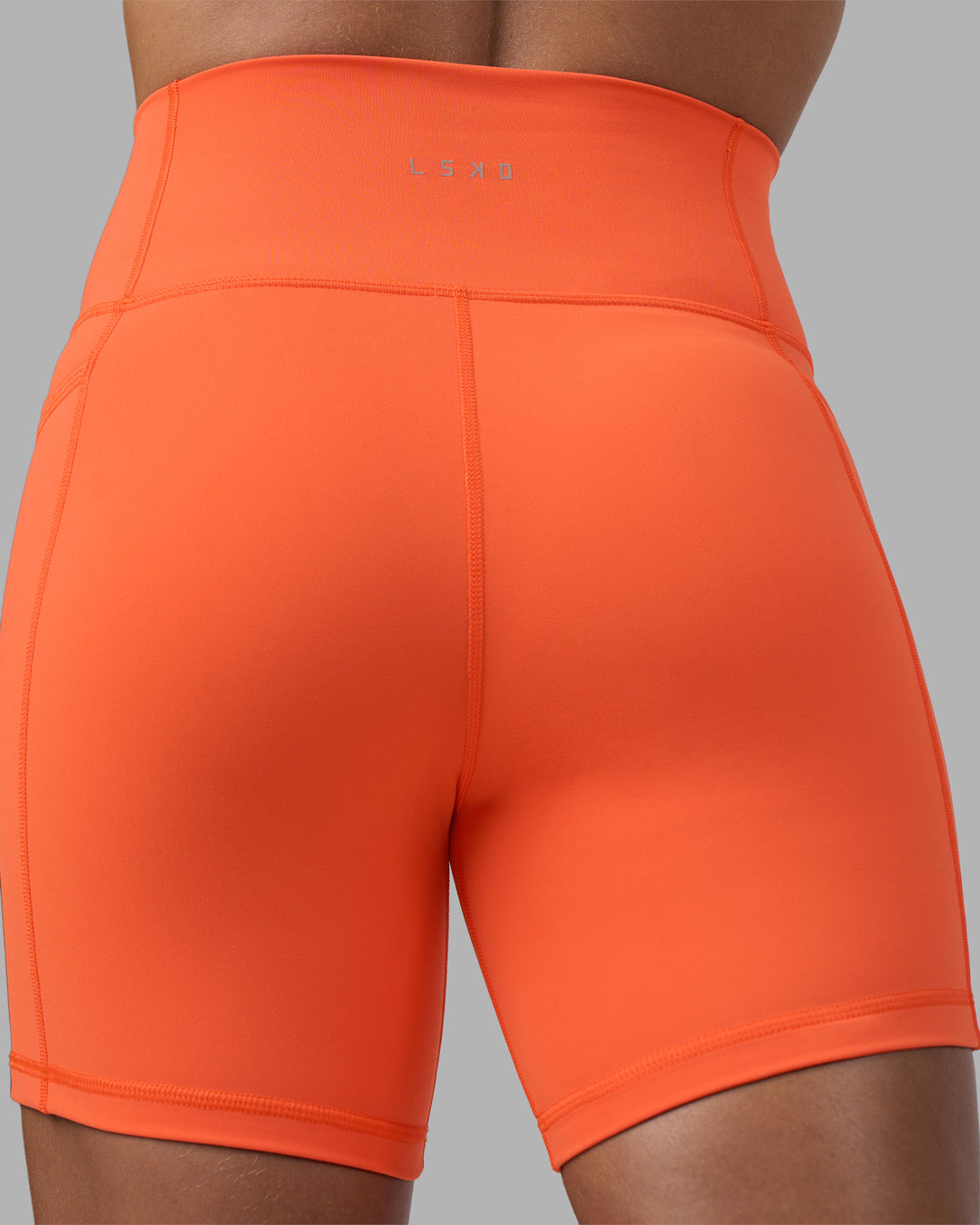 Woman wearing Fusion Ultra High-Rise 6&quot; Short Pockets - Ultra Orange | Model:Katie | Size:S