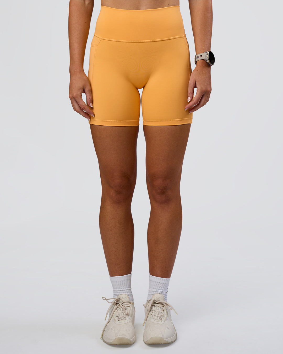 Woman wearing Fusion Ultra High-Rise 6&quot; Short Pockets - Warm Apricot | Model:Emelia | Size:S