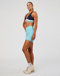 Woman wearing Fusion V-Contour Ultra High-Rise 4” Short Pockets - Baltic Sea | Model:Emelia | Size:S