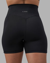 Woman wearing Fusion V-Contour Ultra High-Rise 4” Short Pockets - Black | Model:Charlize | Size:S