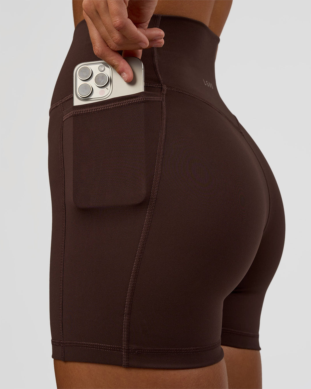 Woman wearing Fusion V-Contour Ultra High-Rise 4” Short Pockets - Hot Chocolate | Model:Amity | Size:S
