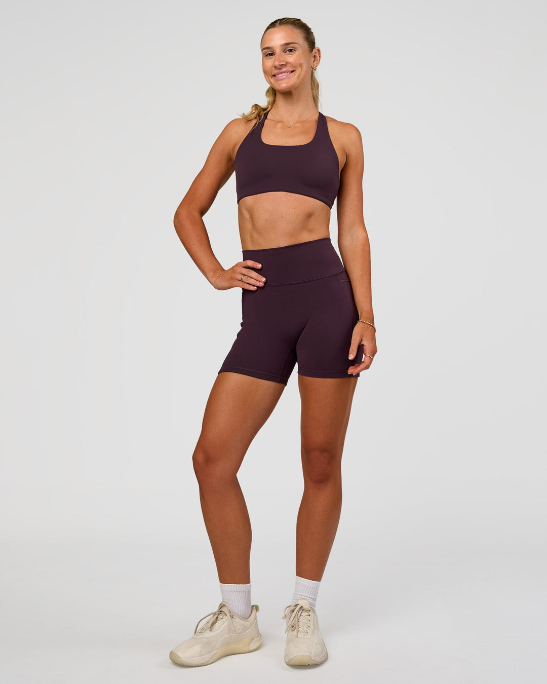 Woman wearing Fusion V-Contour Ultra High-Rise 4” Short Pockets - Midnight Plum | Model:Emelia | Size:S