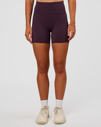Woman wearing Fusion V-Contour Ultra High-Rise 4” Short Pockets - Midnight Plum | Model:Emelia | Size:S