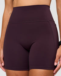 Woman wearing Fusion V-Contour Ultra High-Rise 6" Short Pockets - Midnight Plum | Model:Rhiley | Size:S