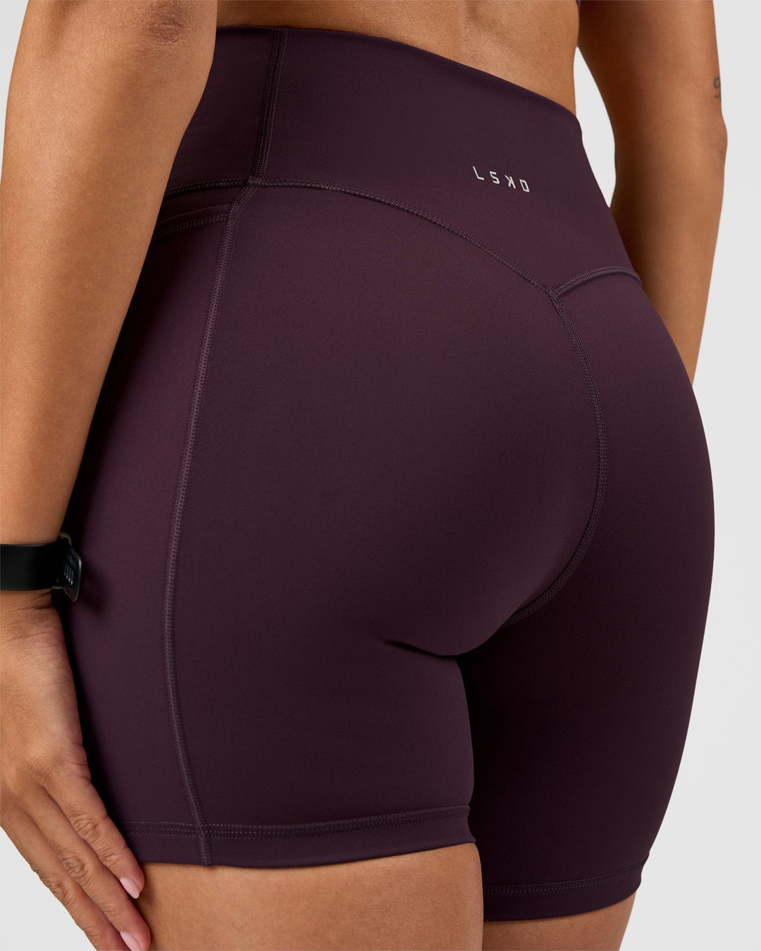 Woman wearing Fusion V-Contour Ultra High-Rise 6" Short Pockets - Midnight Plum | Model:Rhiley | Size:S