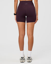 Woman wearing Fusion V-Contour Ultra High-Rise 6" Short Pockets - Midnight Plum | Model:Rhiley | Size:S