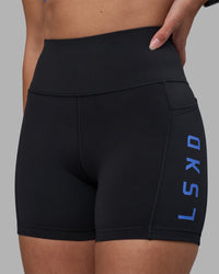 Woman wearing Rep Ultra High-Rise 4" Short Pockets - Black-Power Cobalt | Model:Rhiley | Size:S