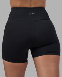 Woman wearing Rep Ultra High-Rise 4" Short Pockets - Black-Power Cobalt | Model:Rhiley | Size:S