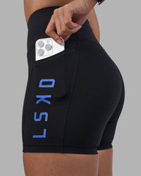 Woman wearing Rep Ultra High-Rise 4" Short Pockets - Black-Power Cobalt | Model:Rhiley | Size:S