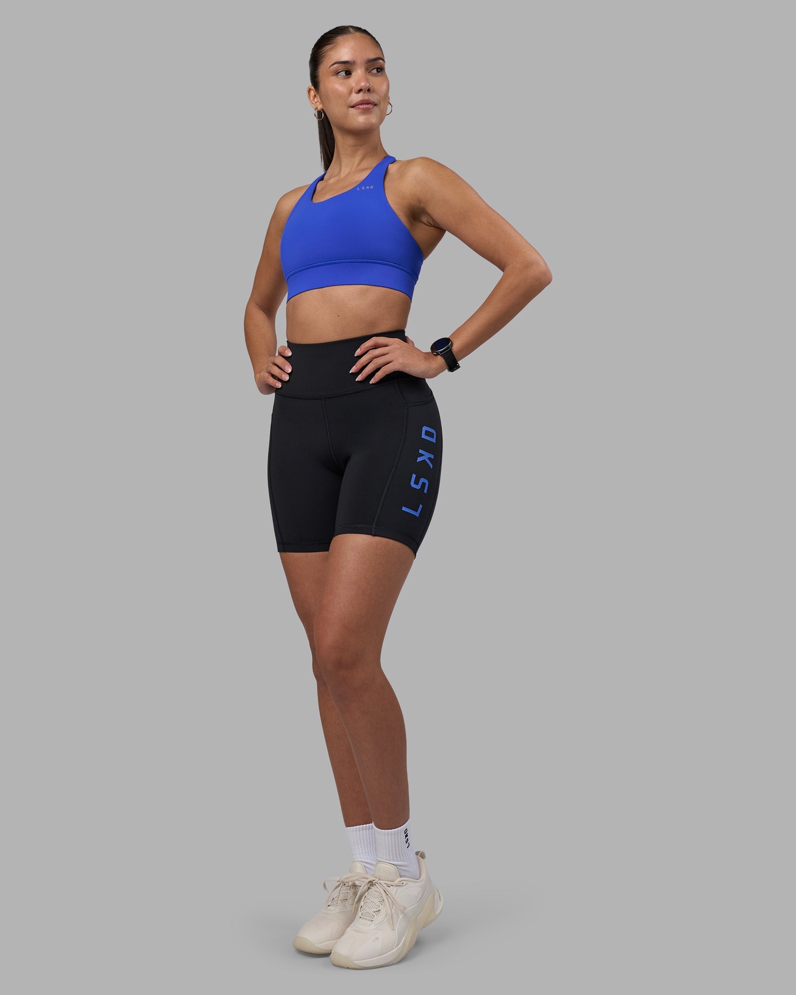 Woman wearing Rep Ultra High-Rise 6" Short Pockets - Black-Power Cobalt | Model:Rhiley | Size:S