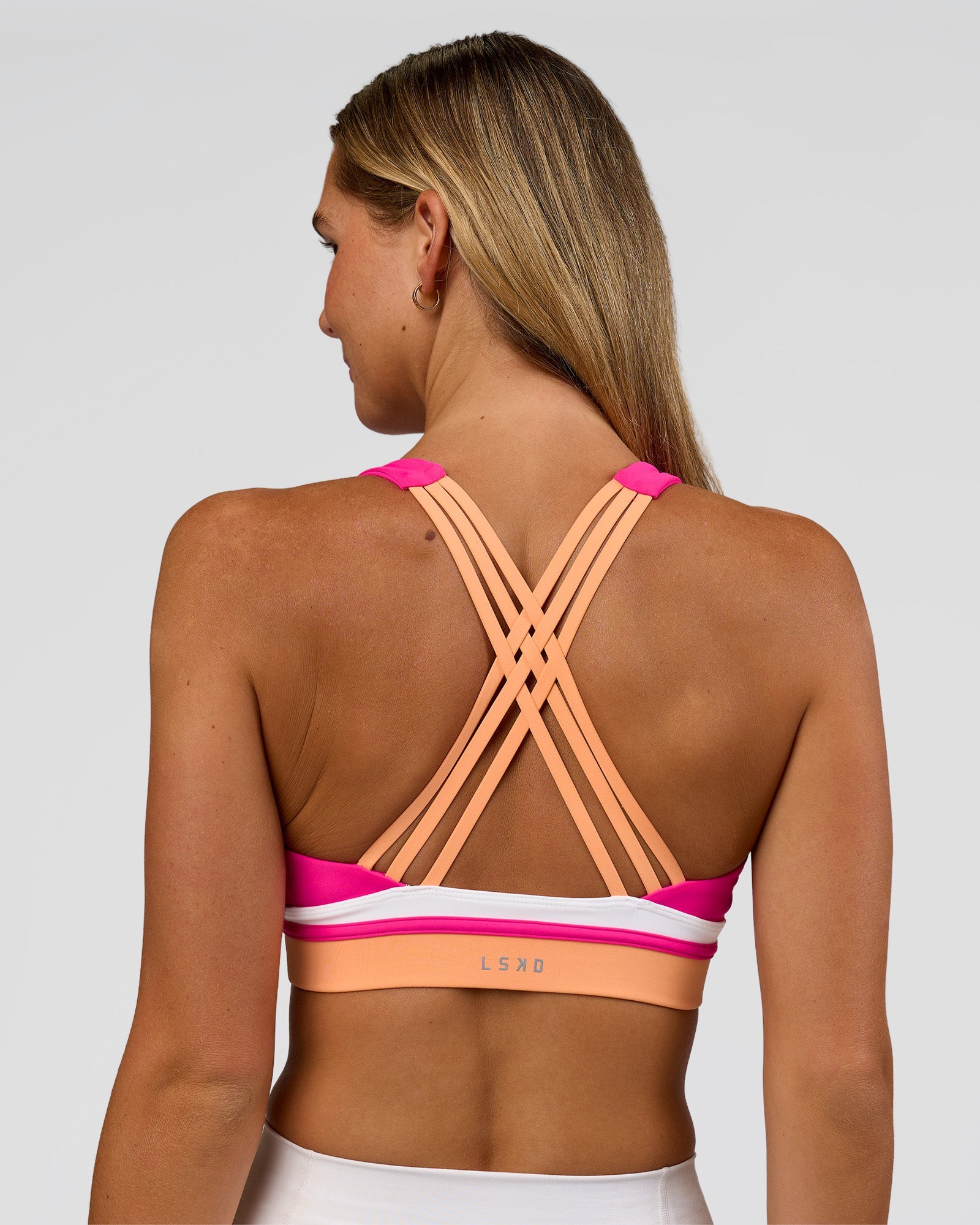 Woman wearing Revitalise Flash Sports Bra - Ultra Pink-Cantaloupe-White | Model:Amity | Size:S