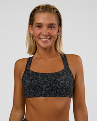 Woman wearing Velocity Sports Bra - Energy Print Black | Model:Amity | Size:S | Thumbnail Index: 1