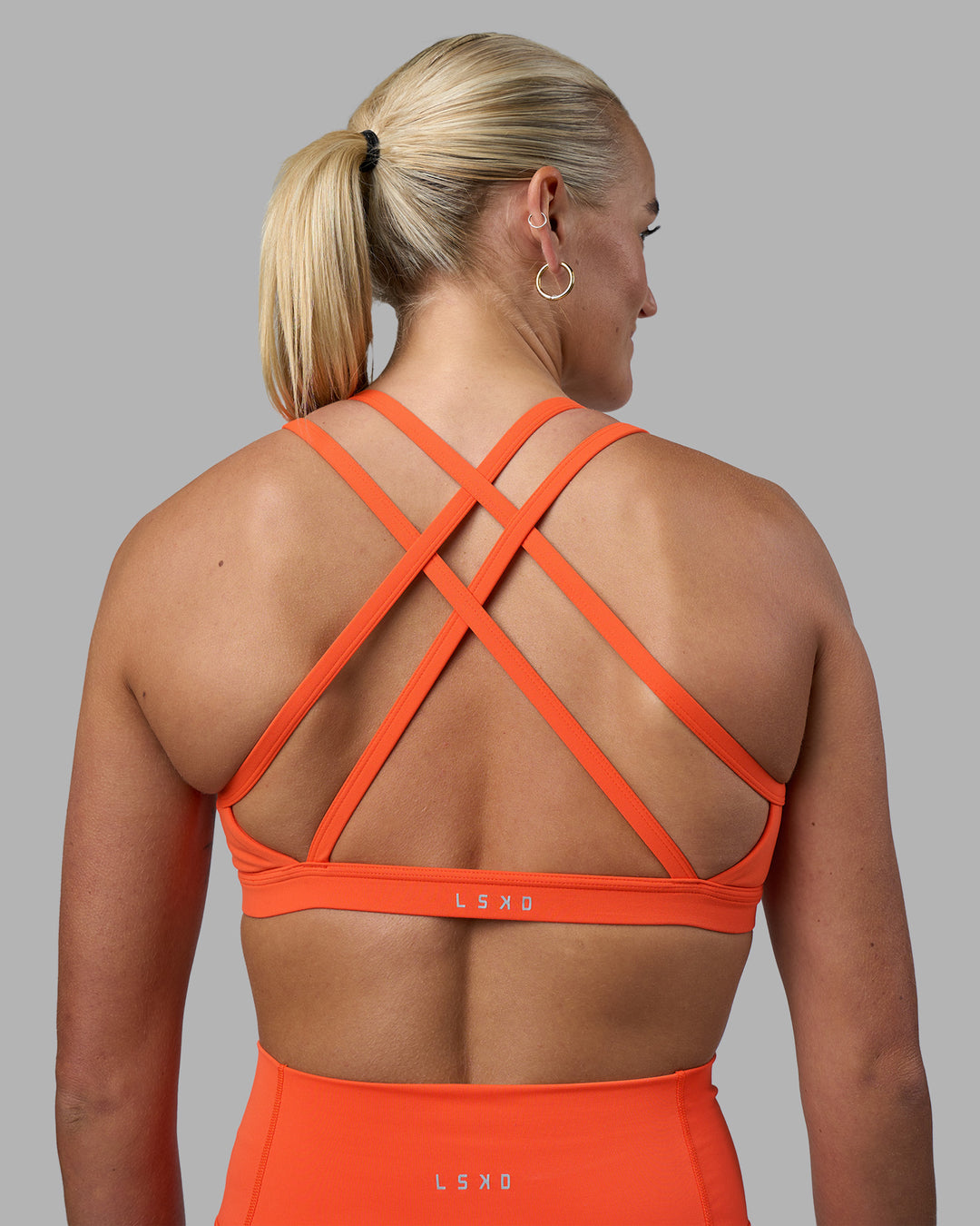 Woman wearing Velocity Sports Bra - Ultra Orange | Model:Katie | Size:S