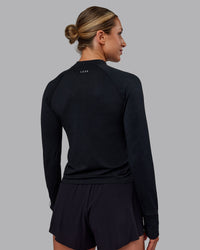 Woman wearing AeroFLX+ Long Sleeve Half Zip - Black Marl | Model:Paris | Size:S