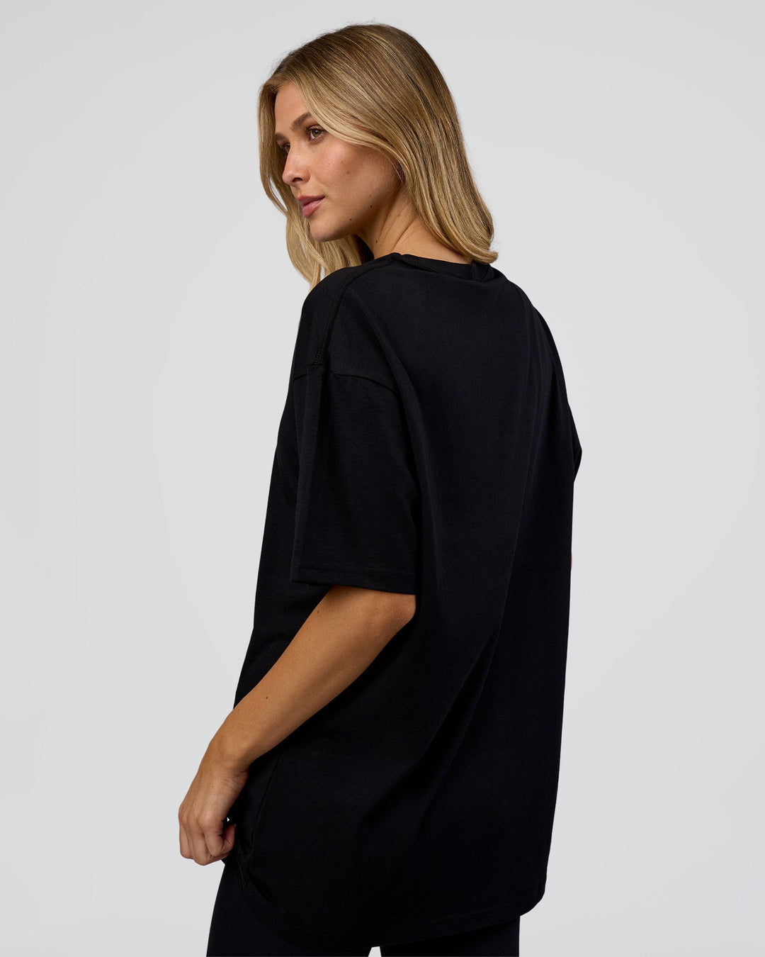 Woman wearing 1% Better Every Day EST FLXCotton Oversized Tee - Black | Model:Leilani | Size:XS