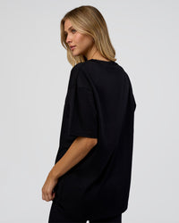 Woman wearing 1% Better Every Day EST FLXCotton Oversized Tee - Black | Model:Leilani | Size:XS