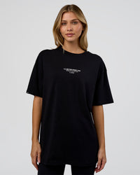 Woman wearing 1% Better Every Day EST FLXCotton Oversized Tee - Black | Model:Leilani | Size:XS