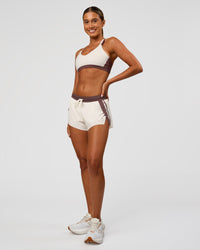 Woman wearing Accelerate 3" Force Mid-Rise Running Short - Cocoa powder-Off White | Model:Charli | Size:XS