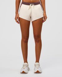 Woman wearing Accelerate 3" Force Mid-Rise Running Short - Cocoa powder-Off White | Set:true | Angle:front | Model:Charli | Size:XS