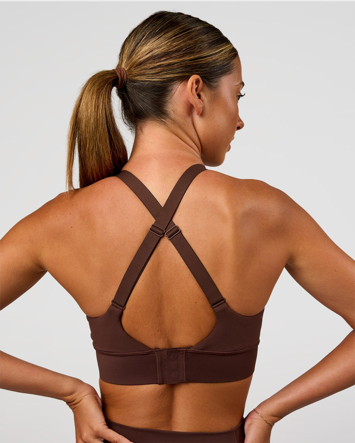 Woman wearing Accelerate Sports Bra - Hot Chocolate | Set:true | Angle:back | Model:Charli | Size:XS