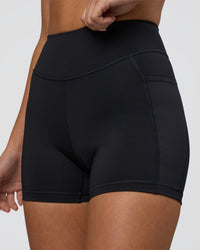 Woman wearing Elite High-Rise 4" Short Pockets - Black | Model:Eliza | Size:XS