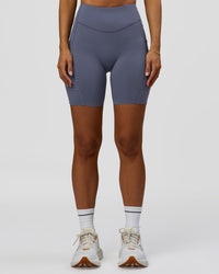 Woman wearing Elite Run High-Rise 7" Short Pockets - Night Shadow | Model:Brylee | Size:XS | Thumbnail Index: 0