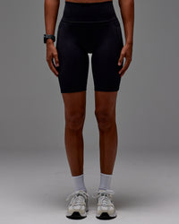 Woman wearing Fusion Ultra High-Rise 9" Short Pockets - Black | Model:Txai | Size:XS