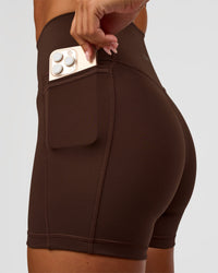 Woman wearing Fusion Ultra High-Rise 4" Short Pockets - Hot Chocolate | Set:true | Angle:closeup | Model:Charli | Size:XS
