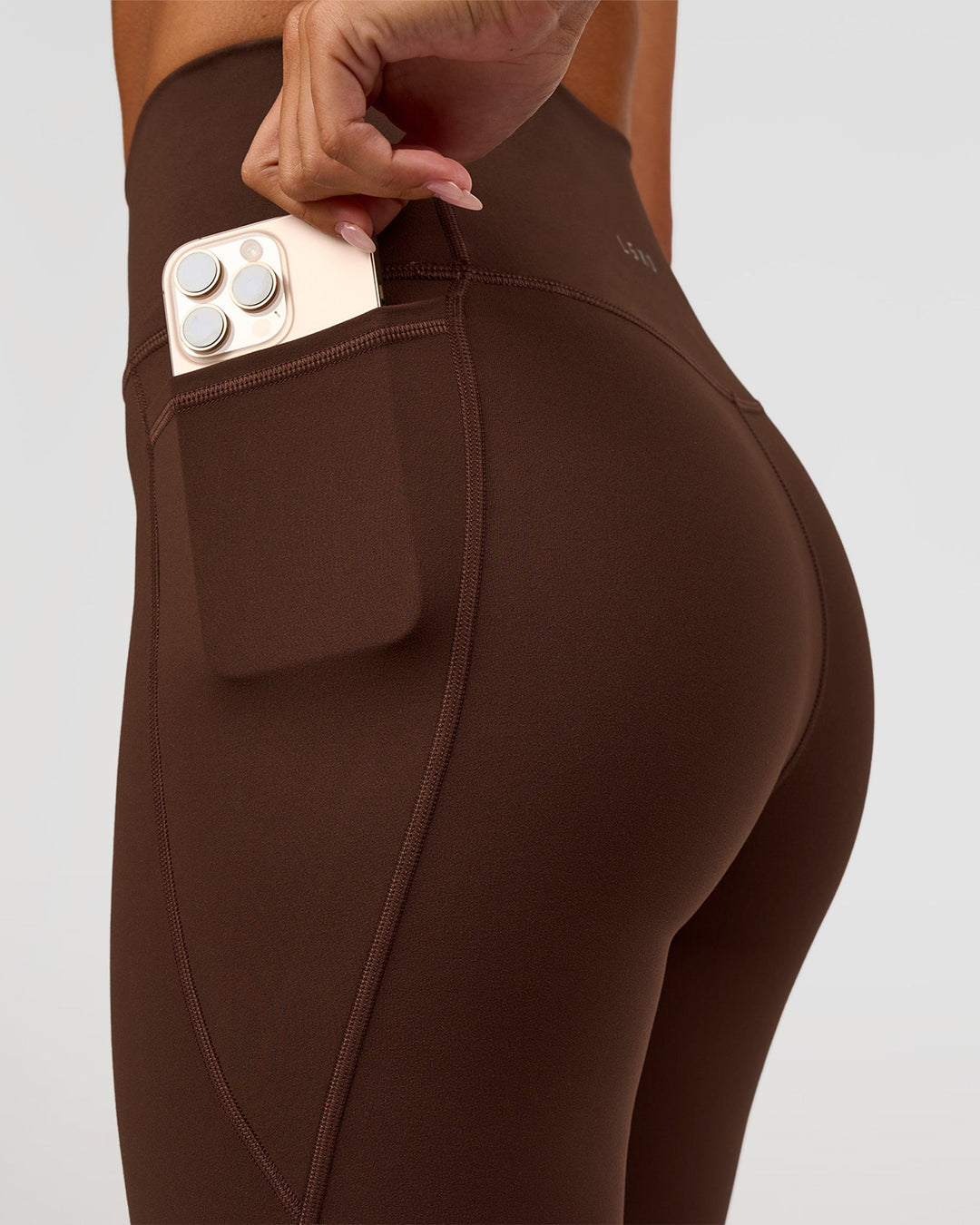 Woman wearing Fusion Ultra High-Rise 9" Short Pockets - Hot Chocolate | Model:Charli | Size:XS