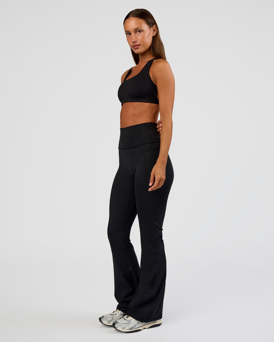 Woman wearing Fusion Ultra High-Rise Flared Petite Legging Pockets - Black | Model:Brylee | Size:XS