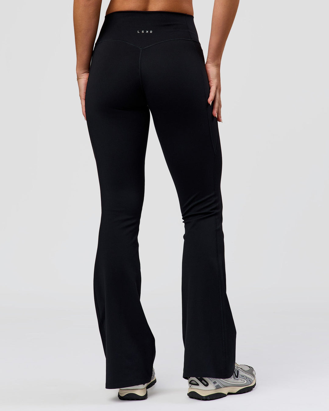 Woman wearing Fusion V-Contour High-Rise Flared Petite Legging Pockets - Black | Model:Issy | Size:XS