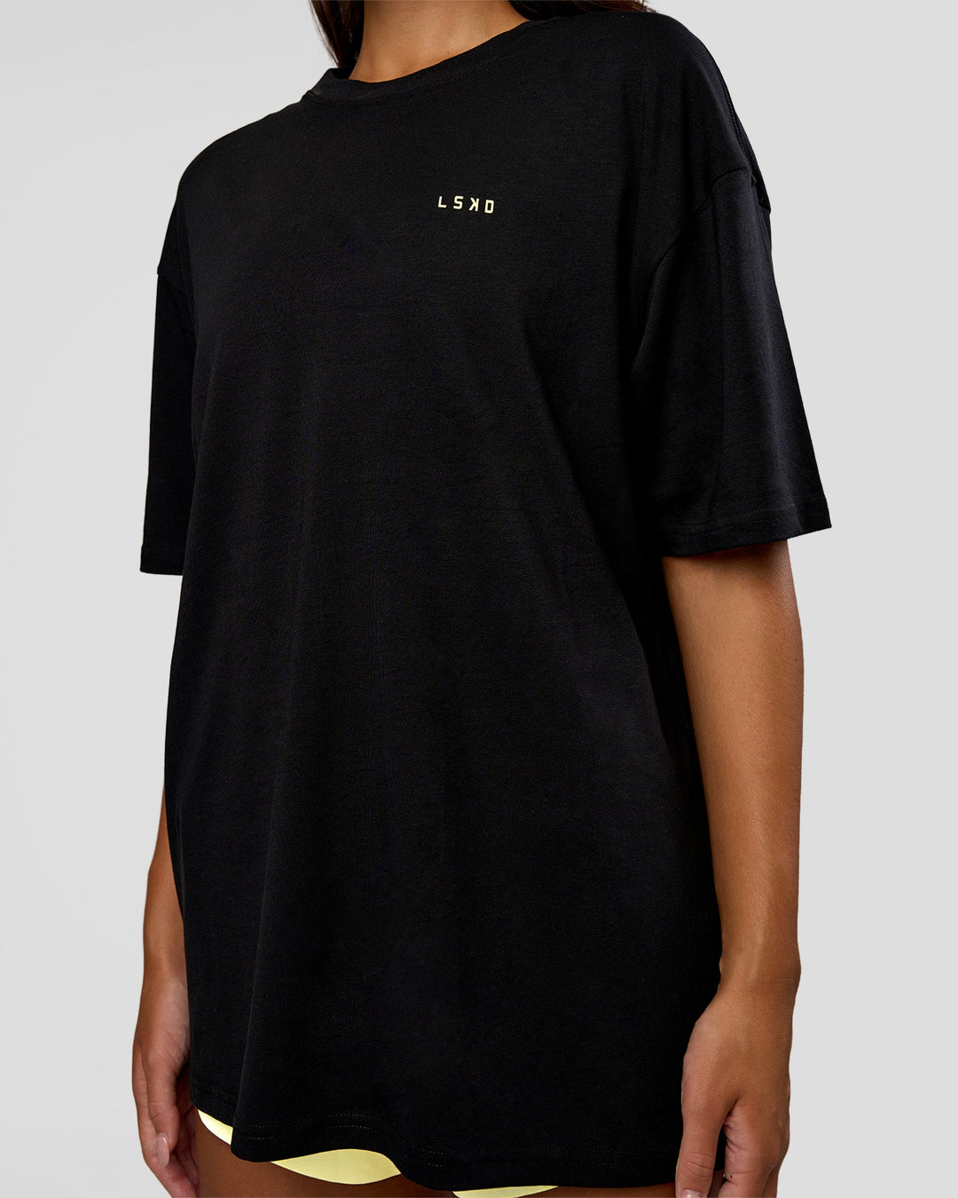 Woman wearing High Run FLXCotton Oversized Tee - Black-Yellow Fizz | Model:Kirstyn | Size:XS