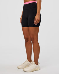 Woman wearing Liberate High-Rise 6" Short Pockets - Black-Candy Pink | Model:Brylee | Size:XS