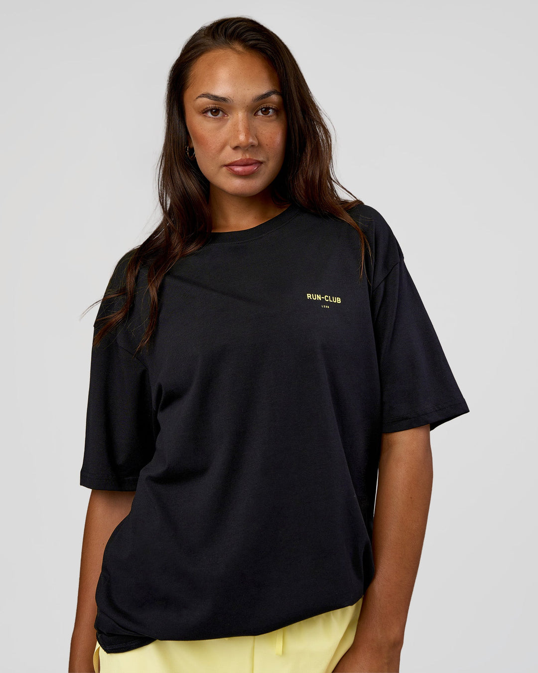 Woman wearing RUN CLUB FLXCotton Tee Oversize - Black-Yellow Fizz | Model:Kirstyn | Size:XS