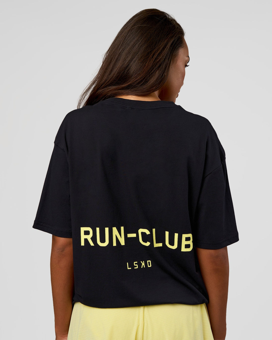 Woman wearing RUN CLUB FLXCotton Tee Oversize - Black-Yellow Fizz | Model:Kirstyn | Size:XS