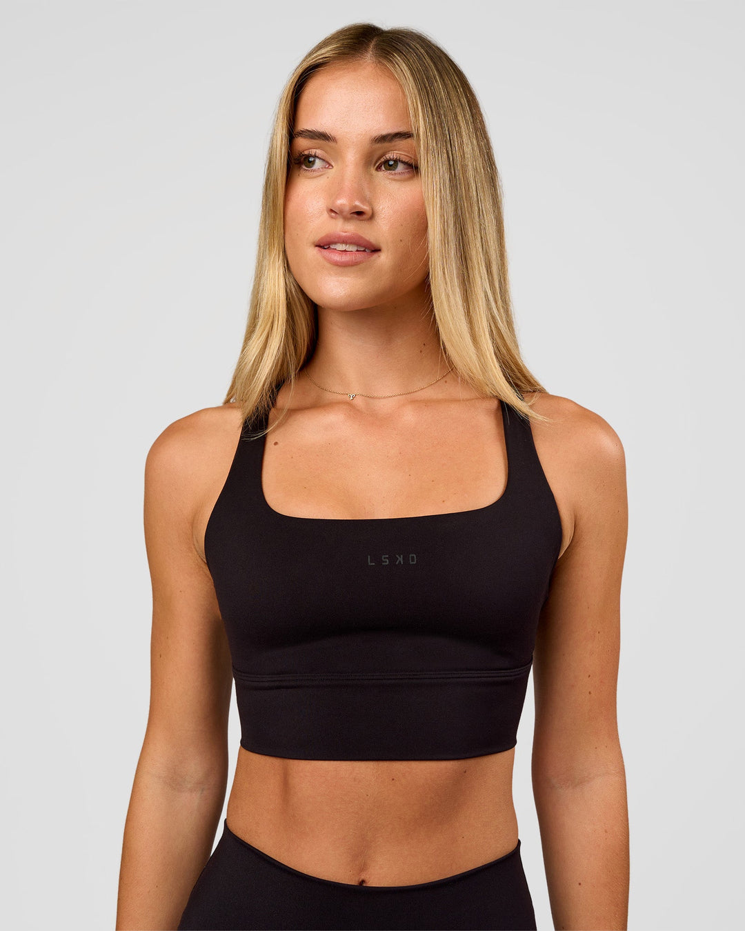 Woman wearing Twist Long Line Sports Bra in Black | Model:Issy | Size:XS