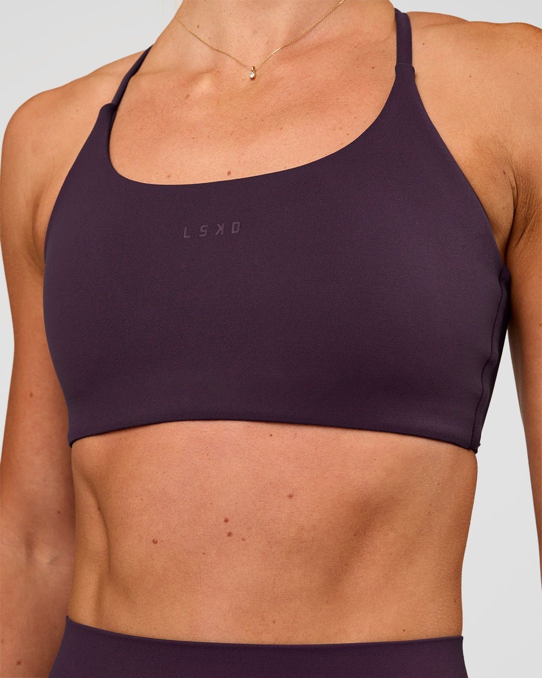 Woman wearing Twist Sports Bra - Midnight Plum | Model:Emelia | Size:XS